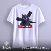 Футболка окак мем подарунок, біла футболка на вішалці, з принтом чорного кота в капюшоні, на фоні з розмитим сірим кольором.