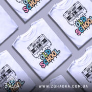 Футболка Old School білого кольору, зображена з фронтального ракурсу на манекені, фон нейтральний, принт з касетою та написом 'OLD SCHOOL' у яскравих кольорах.