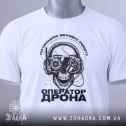 Футболка оператор дрона білого кольору, зображена зверху, на ній підвішений етикет, фон світлий, принт з черепом у навушниках з окулярами, текст "ОПЕРАТОР ДРОНА" під ним.