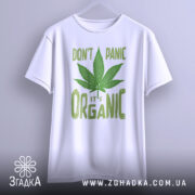 Футболка органік стиль канабіс, біла, підвішена на вішалці, фон світло-сірий, принт зелений з написом 'DON'T PANIC it's ORGANIC' та зображенням листа канабісу.