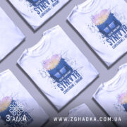 Футболка озеро Синевир білого кольору, зображена з правого ракурсу на манекені, фон нейтральний, принт містить зображення лісу та озера з написом 'Озеро Синевир SYNEVYR Carpathians / Ukraine'.