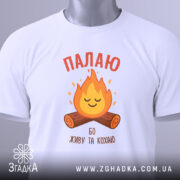 Футболка палаю кохаю, біла, зображена з верхнього ракурсу, на фоні світло-сірого градієнту, принт з вогнем та колодами, на футболці є етикетка з зеленим шнурком.