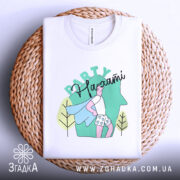 Футболка Party на хаті, біла, зображена зверху на плетеній основі, фон світло-сірий, принт з малюнком хлопця в капелюсі з синім плащем та шортах з сердечками, напис 'Party' зверху.