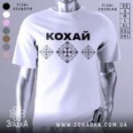 Футболка патріотична кохай, білого кольору, зображена на манекені, фон нейтральний, принт з чорною написом 'КОХАЙ' та вишиванковими елементами у вигляді ромбів.