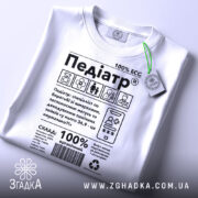 Футболка педіатр білого кольору, зображена зверху, на фоні світлого кольору, принт містить текст і графічні елементи, з написом '100% ECC', на футболці є етикетка з зеленим шнурком.