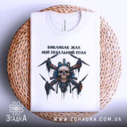 Футболка пекельний птах, біла, складена на плетеній кошику, фон світло-сірий, принт з черепом та пропелерами, деталі в кольорах чорного, червоного та синього.