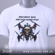 Футболка пекельний птах, біла, складена на поверхні, фон світло-сірий, принт з черепом та пропелерами, на футболці є етикетка з зеленим шнурком.