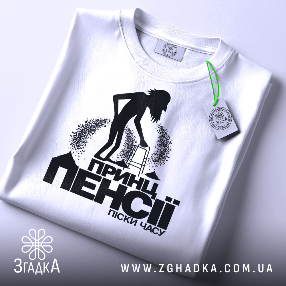 Футболка пенсія піски часу. Біла футболка, складена на плоскій поверхні, фон світло-сірий. Принт чорного кольору з силуетом людини з ходунками, текстом "Принц пенсії піски часу" під малюнком, на футболці є етикетка з зеленим шнурком.