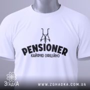Футболка пенсіонер кайфую, біла, зображена зверху, на фоні світло-сірого кольору, з принтом чорного кольору, що містить слово 'PENSIONER' та малюнок візка, з етикеткою зеленого кольору.