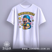 Футболка переможець для дітей. Біла футболка, підвішена на вішалці, з яскравим принтом хлопчика у кепці, що радісно піднімає руку. Принт оточений кольоровими зірочками та усміхненим сонечком. Фон нейтральний, що підкреслює дизайн.