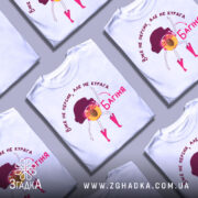 Футболка персик курага багіня, біла футболка на манекені, з принтом жовтого персика з рожевими чоботами та чорним волоссям, фон світло-сірий, текст червоним кольором.