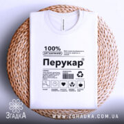 Футболка перукар білого кольору, складена на плетеній основі, фон світло-сірий, принт чорного кольору з написом '100% ОРГАНІЧНИЙ Перукар' та іконками.