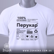 Футболка перукар білого кольору, складена на поверхні, фон світло-сірий, принт чорного кольору з написом '100% ОРГАНІЧНИЙ Перукар' та етикетка з зеленим шнурком.