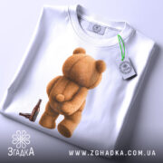 Футболка п’яний ведмідь, біла, зображення ведмедя з пляшкою, ракурс зверху, фон світлий, принт ведмедя з пухнастою текстурою, з етикеткою.