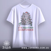 Футболка подарунків захотілося, біла, зображена з фронтального ракурсу, на фоні світло-сірого кольору, принт з котом в червоній шапці, обмотаним гірляндою, з текстом "МЕНІ ПОДАРУНКІВ ЗАХОТІЛОСЯ", підвішена на вішалці.