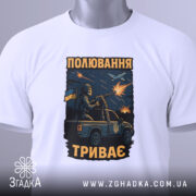 Футболка полювання триває, біла футболка на столі, ракурс зверху, фон світлий, принт з військовим на пікапі, з тегом на зеленій стрічці.