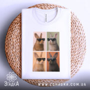 Футболка попарт кролики, біла, складена на плетеній кошику, фон натуральний, принт з чотирма кроликами в окулярах, два з них коричневі, два світлі, видно етикетку.