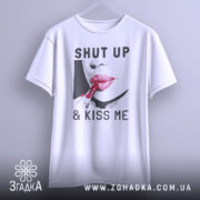 Футболка поцілуй мене, біла, підвішена на вішалці, фон світло-сірий, принт з червоними губами та помадою, текст "SHUT UP & KISS ME".