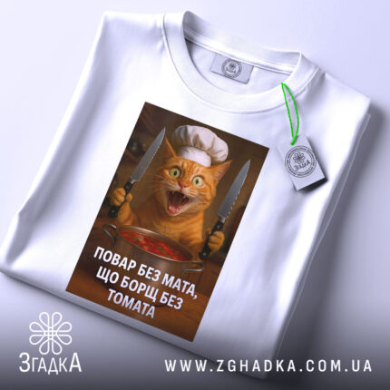 Футболка повар без мата, біла, зображена з верхнього ракурсу, фон світлий, принт з котом у кухарському капелюсі, з прикріпленою етикеткою, яка додає деталі.