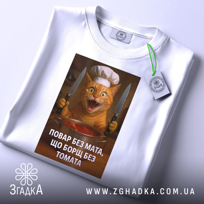 Футболка повар без мата, біла, зображена з верхнього ракурсу, фон світлий, принт з котом у кухарському капелюсі, з прикріпленою етикеткою, яка додає деталі.