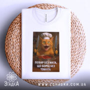 Футболка повар без мата, біла, зображена зверху на плетеній основі, фон натуральний, принт з котом у кухарському капелюсі, який тримає ножі і стоїть над каструлею з борщем.