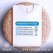 Футболка правила вчителя, біла, зображена на плетеній основі, фон нейтральний, принт з текстом правил вчителя, текст виконаний у синьому та чорному кольорах.