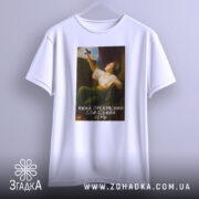 Футболка прекрасний день. Біла футболка, підвішена на вішалці, з принтом жінки, що тримає птаха. Принт розташований по центру, знизу напис: 'Який прекрасний блаженний день'.