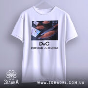 Футболка про гречку, біла, підвішена на вішалці, фон світлий, принт з ножем, гречкою та грошима.