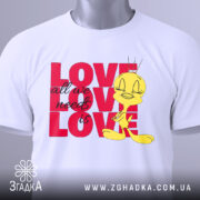 Футболка про кохання, білого кольору, складена на поверхні, фон світлий, принт з жовтою пташкою та написом 'LOVE all we need is LOVE' у червоному кольорі, на футболці є етикетка.