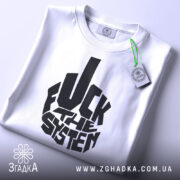 Футболка протестний стиль, біла, зображена зверху, на плоскій поверхні, фон світло-сірий, принт чорний з написом 'FUCK THE SYSTEM', етикетка з зеленим шнурком.