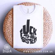 Футболка протестний стиль, біла, складена на плоскій поверхні, фон світло-сірий, принт чорний з написом 'FUCK THE SYSTEM', розташована на плетеній кошику.