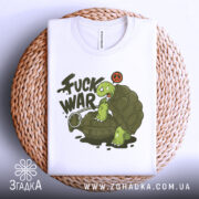 Футболка проти війни. Біла футболка, складена на плетеному кошику, з принтом черепахи на гранаті. Принт яскравий, з написом 'FUCK WAR' та символом миру, фон світлий.