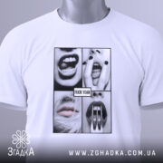 Футболка провокаційний арт, біла, складена на столі, фон світло-сірий, принт з чотирьох чорнобілих зображень з губами і зубами, текст "FUCK YEAH" на чорному фоні, на комірці видна етикетка.