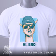 Футболка прикольна лама, біла, складена на столі, зображена з верхнього ракурсу, фон світло-сірий, принт з ламою в блакитній шапці та окулярах, текст "HI, BRO" під малюнком, з етикеткою на шнурку.