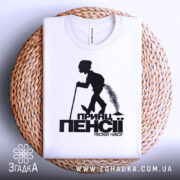 Футболка принц пенсії, біла, зображена зверху, складена на плетеній основі, фон світлий, принт чорного кольору з силуетом постаті, що йде з палицею.