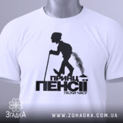 Футболка принц пенсії, біла, зображена зверху, складена на поверхні, фон світлий, принт чорного кольору з силуетом постаті, що йде з палицею, з етикеткою зеленого кольору.