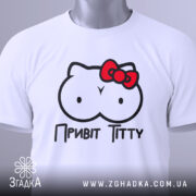 Футболка привіт ціці, біла, зображена на столі, ракурс зверху, фон світлий, принт з малюнком у вигляді двох круглих форм з очима та червоною бантиком, текст "Привіт Тітті" під малюнком, на футболці є етикетка.