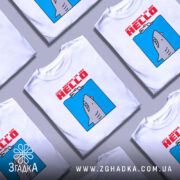 Футболка привіт від акули. Біла футболка на манекені, з принтом акули, що виглядає з блакитного фону. Текст червоним шрифтом говорить 'JUST WANTED TO SAY HELLO'. Фон нейтральний, без зайвих деталей.