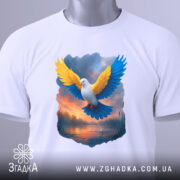 Футболка птах свободи, біла, складена на поверхні, фон світло-сірий, принт з птахом з жовтими та блакитними крилами, з етикеткою на комірці.