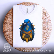 Футболка птах тризуб білого кольору, зображена зверху на плетеній основі, фон світлий, принт з птахом синього кольору з жовтими деталями та гербом України.
