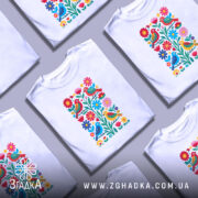 Футболка пташки у квітах, біла, зображена на манекені, фон світло-сірий, принт з яскравими пташками і квітами в червоному, жовтому, синьому та зеленому кольорах.