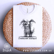 Футболка пухнастий анархіст, білого кольору, складена на плетеній кошику, фон світло-сірий, принт з малюнком пухнастого собаки з великими очима та написом 'Пухнастий анархіст!' під ним.