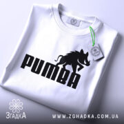 Футболка пумба пародія, біла, складена на столі, фон світлий, принт чорний з написом 'PUMBA' та силуетом борсука, на комірці є етикетка.