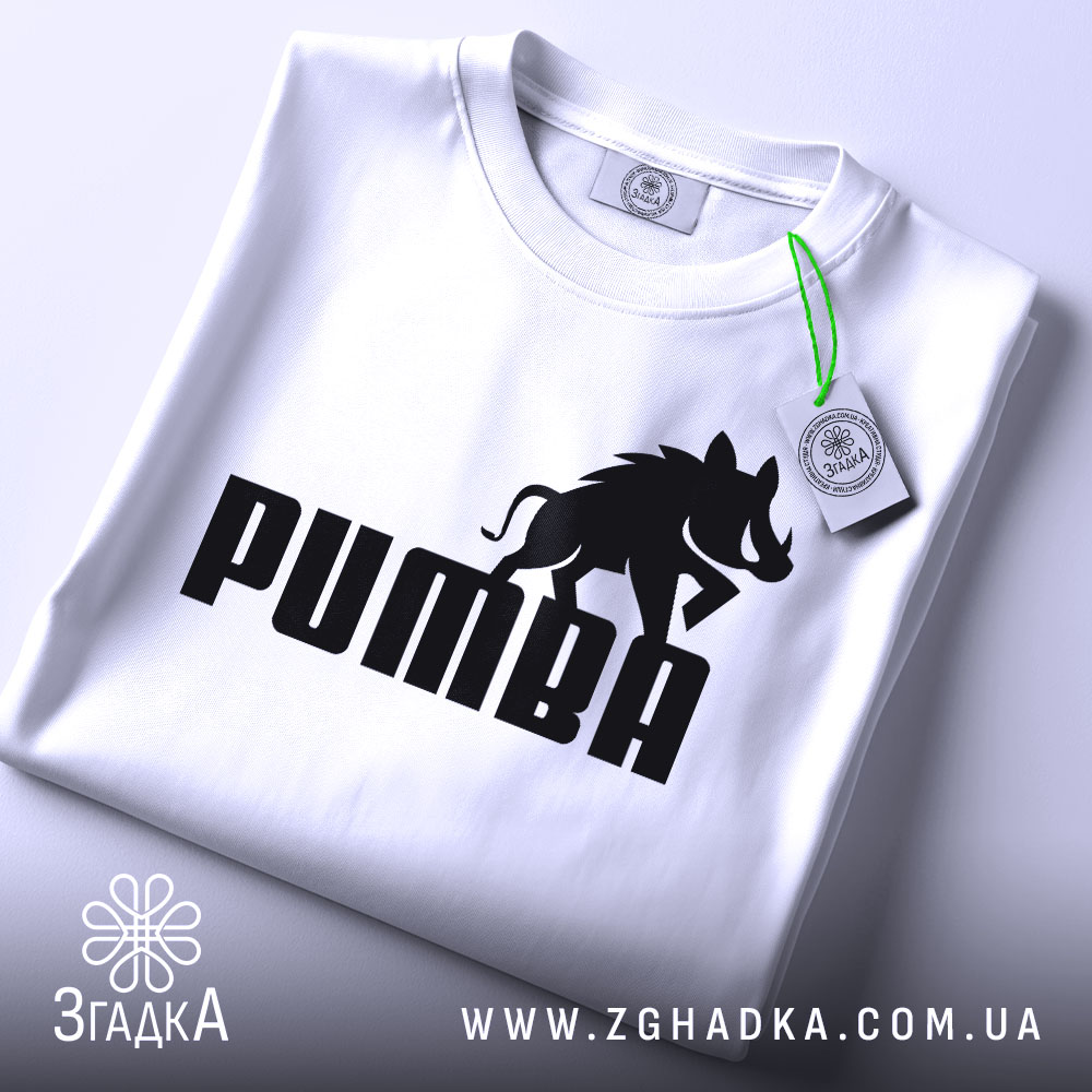 Футболка пумба пародія, біла, складена на столі, фон світлий, принт чорний з написом 'PUMBA' та силуетом борсука, на комірці є етикетка.
