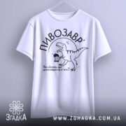 Футболка пивозавр білого кольору, підвішена на вішалці, фон світлий, принт з динозавром, що тримає пиво, текст: "Хто сказав, що динозаври не п'ють?"