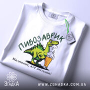 Футболка пивозаврик білого кольору, зображена зверху, на ній видно етикетку, принт з динозавром, що тримає пиво, текст: 'Маленький, але хмільний!'.