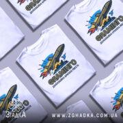 Футболка ракета Фламінго білого кольору, зображена на манекені з правого боку, фон світло-сірий, принт з ракетою, містом та птахом у яскравих кольорах.