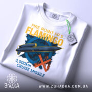 Футболка ракета фламінго, біла, складена на столі, з верхнього ракурсу, фон світло-сірий, принт зображує ракету та текст "3,000km CRUISE MISSILE" у жовтому та блакитному кольорах, з етикеткою на рукаві.