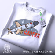 Футболка Ракета Нептун білого кольору, зображена зверху, на столі, фон світло-сірий, принт з ракетою та написом 'ДОВГИЙ НЕПТУН' у червоному кольорі, з зеленим ярликом.