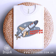 Футболка Ракета Нептун білого кольору, зображена зверху на плетеній кошику, фон світло-сірий, принт з ракетою та написом 'ДОВГИЙ НЕПТУН' у червоному кольорі.